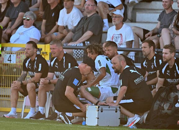 12.08.2026; Velbert; Fussball, Herren, Saison 2026 2027, Testspiel SSVg Velbert vs. Borussia Moenchengladbach Wael Mohya (Gladbach) sitzt verletzt auf der Bank. Dirk Mueller (Physiotherpeut Gladbach, li.) und Nils Haupt (Mannschaftsarzt Gladbach, re.) kuemmern sich um ihn. Sein linker Oberschenkel wurde bandagiert. DFL regulations prohibit any use of photographs as image sequences and or quasi-video. IMS Arena Nordrhein-Westfalen Deutschland *** August 12, 2026 Velbert Soccer, Men’s, 2026–2027 Season, Friendly Match: SSVg Velbert vs. Borussia Mönchengladbach Wael Mohya (Gladbach) is sitting on the bench injured Dirk Mueller, Gladbach’s physical therapist, left, and Nils Haupt, Gladbach team doctor, right, are taking care of him. His left thigh was bandaged. DFL regulations prohibit any use of photographs as image sequences and or quasi-video. IMS Arena, North Rhine-Westphalia, Germany