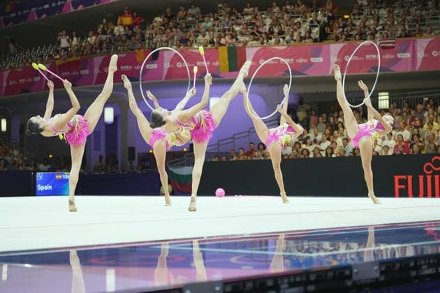 Das spanische Gruppenensemble zeigt eine synchrone Hebefigur mit Reifen und Keulen auf dem Wettkampfteppich der Festhalle Frankfurt. Auf der Anzeigetafel ist der Teamname Spain zu lesen, im Hintergrund verfolgt ein volles Publikum die Darbietung. Spaniens Gruppe-Ensemble mit Reifen und Keulen bei der WM Frankfurt *** The Spanish Ensemble group performs a synchronized lift routine with hoops and clubs on the competition floor of the Festhalle in Frankfurt. The scoreboard displays the team name Spain, and in the background, a packed audience watches the Spanish Ensemble group’s performance with hoops and clubs at the World Championships in Frankfurt. Copyright: xspeedshotx