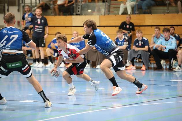 Ein Spieler von HK Malmö im weißen Trikot kämpft mit dem Ball in der Hand gegen einen Skive-fH-Spieler, der ihn von hinten bedrängt. Links ist Nickolei Jensen ( 47; Skive fH) von hinten zu sehen. HK Malmö im Zweikampf gegen Skive fH in der Hansehalle *** An HK Malmö player in a white jersey battles for the ball against a Skive fH player who is pressuring him from behind. On the left, Nickolei Jensen (No. 47, Skive fH) can be seen from behind as HK Malmö goes head-to-head with Skive fH at the Hansehalle. Copyright: xspeedshotx
