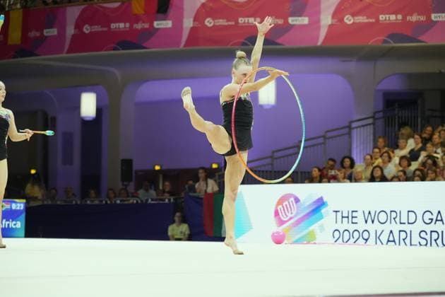 Eine Gymnastin führt eine Reifen-Übung mit hohem Beinbalanceelement in der Festhalle Frankfurt aus. Im Hintergrund ist eine weitere Athletin mit Keulen zu sehen. Gymnastin mit Reifen bei der Weltmeisterschaft der rhythmischen Sportgymnastik in Frankfurt *** A gymnast performs a hoop routine featuring a high-leg balance element at the Festhalle in Frankfurt. In the background, another athlete can be seen performing with clubs. A gymnast with a hoop at the Rhythmic Gymnastics World Championships in Frankfurt Copyright: xspeedshotx