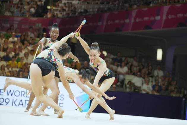 Eine Gruppe von Gymnastinnen führt eine synchronisierte Keulen-Übung in der Festhalle Frankfurt auf. Die Athletinnen bewegen sich in enger Formation, während das vollbesetzte Publikum im Hintergrund die Szene einrahmt. Gruppenübung mit Keulen bei der Rhythmischen Sportgymnastik WM 2026 *** A group of gymnasts performs a synchronized clubs routine at the Festhalle in Frankfurt. The athletes move in tight formation, while the packed audience in the background frames the scene. Group clubs routine at the 2026 Rhythmic Gymnastics World Championships Copyright: xspeedshotx