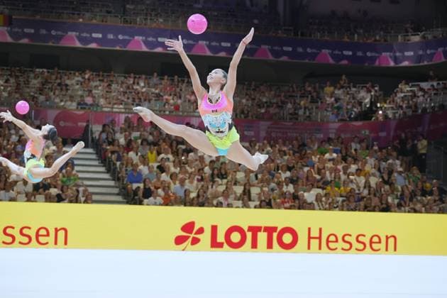 Zwei Turnerinnen führen in der vollbesetzten Festhalle Frankfurt eine synchronisierte Sprungkombination mit pinken Bällen aus. Die vordere Turnerin zeigt einen ausgestreckten Spagat-Sprung, während der Ball in der Luft geworfen wird. Gruppenübung mit Ball bei der Rhythmischen Sportgymnastik-WM in Frankfurt *** Two gymnasts perform a synchronized jump combination with pink balls in Frankfurt’s packed Festhalle. The gymnast in the front performs a straddle jump while the ball is thrown into the air. Group routine with a ball at the Rhythmic Gymnastics World Championships in Frankfurt Copyright: xspeedshotx