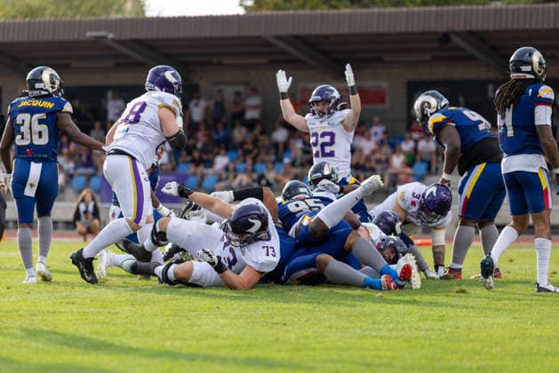 Players from the Alpine Rams and Vienna Vikin gs contest a loose ball. A mass of players grapples on the ground following a tackle, while nearby teammates stand watching the play unfold. Spectators fill the stadium seating in the background under daylight.Vienna Vikings at Alpine Rams, American Football, American Football League Europe, Week 13, 2026, 8.8.2026, Copyright: xPFA RicoxDoninellix