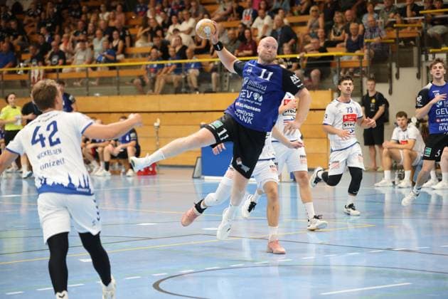 Kristoffer Jessen ( 11; Grindstedt GIF) zieht aus dem Sprung ab und hält den Ball wurfbereit über dem Kopf, während Lukas Kingsley Emdorf ( 73; VfL Lübeck-Schwartau) und Einar Nickelsen ( 42; VfL Lübeck-Schwartau) die Szene beobachten. Im Hintergrund verfolgen weitere Spieler beider Teams sowie eine gut gefüllte Tribüne das Geschehen. Kristoffer Jessen ( 11; Grindstedt GIF) beim Sprungwurf in der Hansehalle *** Kristoffer Jessen, 11, of Grindstedt GIF, jumps and holds the ball above his head, ready to shoot, while Lukas Kingsley Emdorf 73 of VfL Lübeck Schwartau and Einar Nickelsen 42 of VfL Lübeck Schwartau watch the action. In the background, other players from both teams, as well as a packed stands, watch the action unfold. Kristoffer Jessen 11 of Grindstedt GIF takes a jump shot at the Hansehalle. Copyright: xspeedshotx