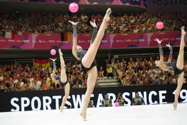 Drei Turnerinnen einer Gruppe führen synchron eine Ballübung in der Festhalle Frankfurt aus, wobei die pinken Bälle hoch in die Luft geworfen werden. Die Athletinnen zeigen dabei ausdrucksstarke Streckspreizsprünge vor ausverkauftem Publikum. Gruppenübung mit Ball bei der Rhythmischen Sportgymnastik WM 2026 in Frankfurt *** Three gymnasts from a group perform a synchronized ball routine at the Festhalle in Frankfurt, throwing the pink balls high into the air. The athletes perform expressive stretch-and-spread jumps in front of a sold-out audience. Group routine with ball at the 2026 Rhythmic Gymnastics World Championships in Frankfurt Copyright: xspeedshotx