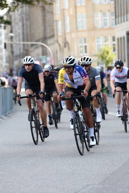 Eine Gruppe von Radsportlern fährt dicht gedrängt durch die Straßen Hamburgs beim Rathausmarkt. Im Vordergrund ist ein Fahrer im gelb-weißen INEOS-Trikot zu sehen, flankiert von weiteren Fahrern. Radsportfeld bei der EuroEyes Cyclassics in Hamburg *** A group of cyclists rides in tight formation through the streets of Hamburg near Rathausmarkt. In the foreground is a rider in the yellow-and-white INEOS jersey, flanked by other riders. The peloton at the EuroEyes Cyclassics in Hamburg Copyright: xspeedshotx xSarahxWolfx
