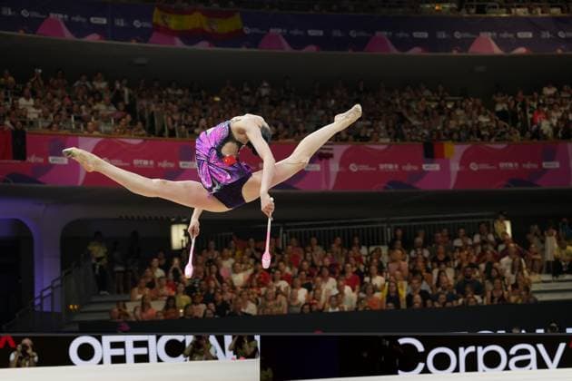Eine Gymnastin aus China führt bei der Weltmeisterschaft der Rhythmischen Sportgymnastik in der Festhalle Frankfurt einen Spagat-Sprung mit zwei Keulen aus. Das vollbesetzte Publikum verfolgt die Übung im Hintergrund. Chinesische Gymnastin mit Keulen beim Sprung bei der Rhythmischen WM Frankfurt *** A gymnast from China performs a split jump with two clubs at the Rhythmic Gymnastics World Championships in Frankfurt’s Festhalle. The packed audience watches the routine in the background. Chinese gymnast with clubs performing a jump at the Rhythmic Gymnastics World Championships in Frankfurt Copyright: xspeedshotx