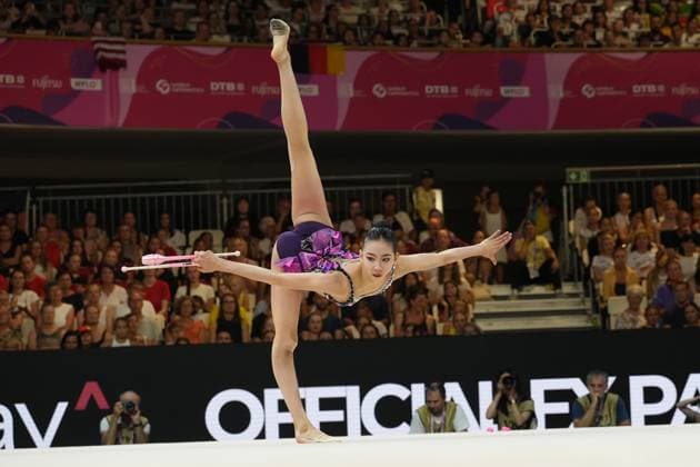 Gymnastin aus aus China führt bei der Weltmeisterschaft der Rhythmischen Sportgymnastik 2026 in der Festhalle Frankfurt eine Waage mit senkrecht erhobenem Bein aus, während sie zwei Keulen in der Hand hält. Das violett-pink besetzte Wettkampf-Trikot und die ausgestreckte Körperhaltung unterstreichen die Präzision der Übung vor vollem Zuschauerrang. Gymnastin aus China mit Keulen in spektakulärer Balance-Pose bei der Rhythmischen Sportgymnastik WM *** A gymnast from China performs a balance move with one leg raised vertically at the 2026 Rhythmic Gymnastics World Championships in Frankfurt’s Festhalle, while holding two clubs in her hands. The competition leotard, accented with purple and pink, and her extended posture highlight the precision of the routine in front of a packed audience. A gymnast from China strikes a spectacular balancing pose with clubs at the Rhythmic Gymnastics World Championships. Copyright: xspeedshotx