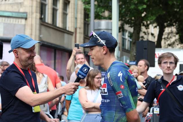 Paul Magnier (Soudal Quick-Step) gibt dem NDR-Reporter ein Interview am Rathausmarkt Hamburg. Im Hintergrund verfolgen zahlreiche Zuschauer die Szene. Paul Magnier (Soudal Quick-Step) im NDR-Interview bei den Cyclassics Hamburg *** Paul Magnier of Soudal Quick-Step gives an interview to an NDR reporter at Hamburg s Rathausmarkt. In the background, numerous spectators watch the scene of Paul Magnier of Soudal Quick-Step being interviewed by NDR at the Cyclassics Hamburg. Copyright: xspeedshotx xSarahxWolfx