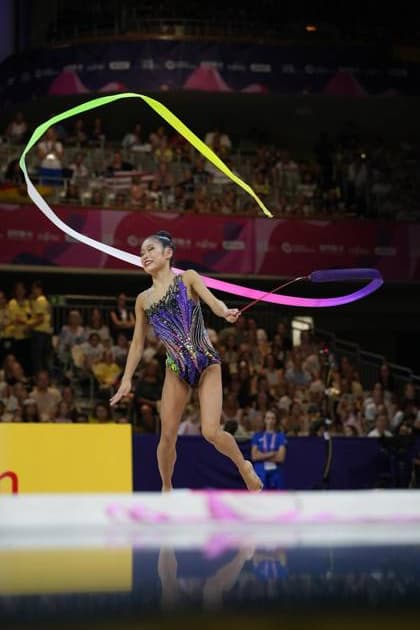 Eine Gymnastin von der USA führt in der Festhalle Frankfurt eine Bandübung bei der Weltmeisterschaft der rhythmischen Sportgymnastik 2026 aus. Das farbige Band beschreibt eine weite Schleife über ihrem Kopf, während sie auf einem Bein balanciert. Rhythmische Sportgymnastik mit Band bei der WM in Frankfurt *** A gymnast from the U.S. performs a ribbon routine at the 2026 World Championships in Rhythmic Gymnastics at the Festhalle in Frankfurt. The colorful ribbon forms a wide loop above her head as she balances on one leg. Rhythmic gymnastics ribbon routine at the World Championships in Frankfurt Copyright: xspeedshotx
