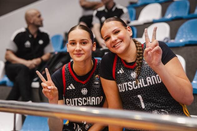 Zwei Spielerinnen von Team Deutschland u16w zeigen lächelnd das Victory-Zeichen in der Pitesti Arena. Im Hintergrund sind blaue Zuschauerränge und eine weitere Person zu sehen. Zwei Deutschland-Spielerinnen posieren mit Victory-Zeichen in Pitesti *** Two players from Team Germany U16w smile as they make the victory sign at the Pitesti Arena. In the background, blue spectator stands and another person can be seen. Two German players pose with the victory sign in Pitesti. Copyright: xJoelxKruehlerx