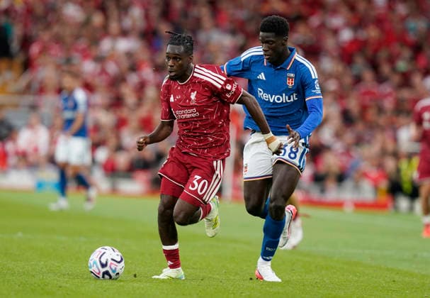 Liverpool, England, 16th August 2026. Jeremie Frimpong of Liverpool (L) is challenged by Assane Diao of Como during the Liverpool vs Como 1907 Pre Season Friendly match at Anfield, Liverpool. Picture credit should read: Andrew Yates Sportimage EDITORIAL USE ONLY. No use with unauthorised audio, video, data, fixture lists, club league logos or live services. Online in-match use limited to 120 images, no video emulation. No use in betting, games or single club league player publications. SPI_019_AY_LIVERPOOL_COMO SPI-4910-0025
