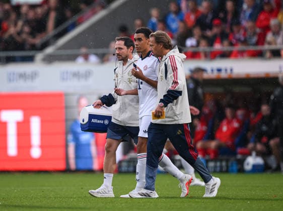 Fussball Testspiel 1. Bundesliga 2026 2027 18.08.2026 1. FC Heidenheim - FC Bayern Muenchen Jamal Musiala (Mitte, FC Bayern Muenchen) erneut mit einer Kreislaufzusammenbruch wird von Mannschaftsarzt Dr. Peter Ueblacker (re, FC Bayern Muenchen) vom Platz gefuehrt *** Soccer Friendly Match 1, Bundesliga 2026–2027, August 18, 2026: 1. FC Heidenheim vs. FC Bayern Munich; Jamal Musiala (center), FC Bayern Munich suffers another circulatory collapse; team doctor Dr. Peter Ueblacker attends to the player; FC Bayern Munich player is led off the field