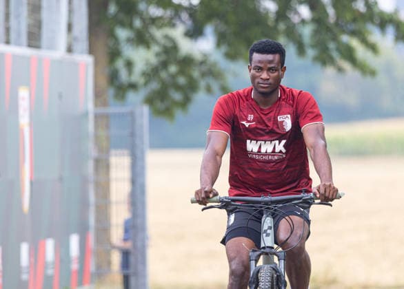 Uchenna Ogundu (FC Augsburg 39) mit dem Fahrrad auf dem Weg zum Trainingsplatz; FC Augsburg, Training, *** Uchenna Ogundu, FC Augsburg 39, riding his bike on the way to the FC Augsburg training field, Training,