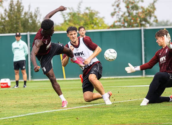 Nathanael Mbuku (FC Augsburg 34), akrobatischer Torschuß gegen Finn Dahmen (Torwart FC Augsburg 1) und Keven Schlotterbeck (FC Augsburg 31); FC Augsburg, Training, *** Nathanael Mbuku (FC Augsburg 34), acrobatic shot on goal against Finn Dahmen (FC Augsburg 1) and Keven Schlotterbeck (FC Augsburg 31), FC Augsburg, practice,