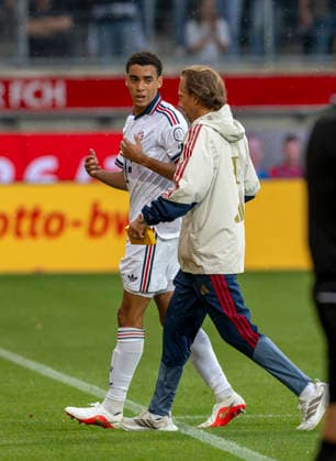 18.08.2026, Fussball Bundesliga 2026 2027, Testspiel, 1.FC Heidenheim - FC Bayern München, in der Voith-Arena Heidenheim, nach seinem erneuten Zusammenbruch während des Spieles, wird Jamal Musiala (li, Bayern München) vom Mannschaftsarzt Prof. Dr. Peter Ueblacker versorgt und vom Platz geführt. *** August 18, 2026, 2026–2027 Bundesliga season, friendly match, 1. FC Heidenheim vs. FC Bayern Munich, at the Voith Arena in Heidenheim; after collapsing again during the game, Jamal Musiala (left), of Bayern Munich, is treated by team doctor Prof. Dr. Peter Ueblacker and led off the field