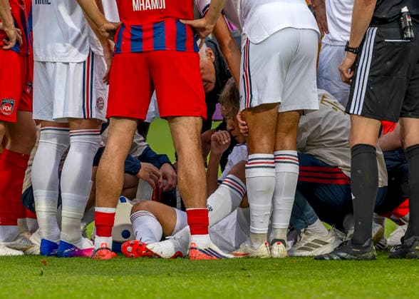 18.08.2026, Fussball Bundesliga 2026 2027, Testspiel, 1.FC Heidenheim - FC Bayern München, in der Voith-Arena Heidenheim, nach seinem erneuten Zusammenbruch während des Spieles, wird Jamal Musiala (am Boden mitte, Bayern München) vom Mannschaftsarzt versorgt. Spieler beider Mannschaften bilden eine Sichtschutzmauer für den Kollegen. Auch Schiedsrichter Fraih Khalifah Salim Al Jaloud steht dabei. *** August 18, 2026, 2026–2027 Bundesliga, Friendly Match, 1. FC Heidenheim vs. FC Bayern Munich, at the Voith Arena in Heidenheim; after collapsing again during the game, Jamal Musiala lies on the ground in the middle, Bayern Munich’s team doctor is treating him; players from both teams form a screen to shield their teammate. Referee Fraih Khalifah Salim Al Jaloud is also standing nearby.