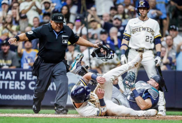 Home plate umpire Adrian Johnson watches as Milwaukee Brewers first baseman Jake Bauers (C) scores on Seattle Mariners catcher Cal Raleigh (R) in the first inning of the MLB, Baseball Herren, USA game between the Seattle Mariners and the Milwaukee Brewers at American Family Field in Milwaukee, Wisconsin on Tuesday, August 18, 2026.  MIL20260818809 TANNENxMAURY