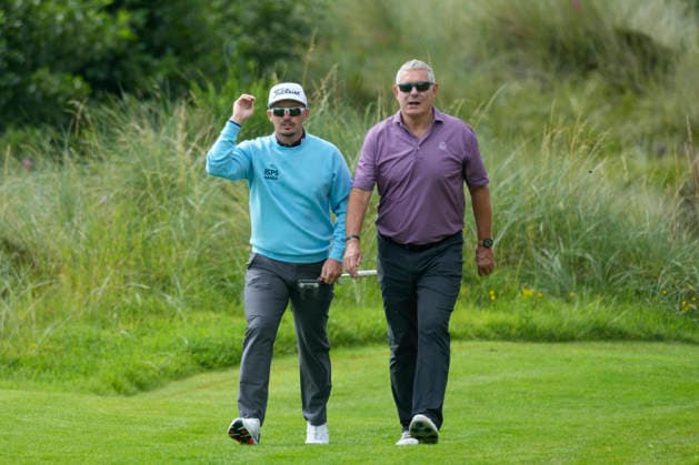 BALMEDIE, SCOTLAND - AUG 19: Ewen Ferguson (SCO) speaks with Gavin Hastings, former Scottish Rugby player, as they walk to the 6th green during the Pro-Am at the 2026 Nexo Championship at the Trump International Golf Links, Balmedie on August 19, 2026 in Aberdeenshire, Scotland The 2026 Nexo Championship