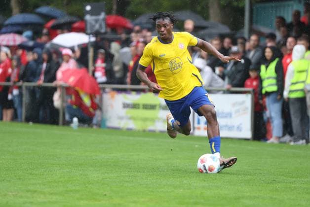 Ein Spieler von Rot-Weiss Essen treibt den Ball am Willi-Lemkens Sportpark in Sonsbeck vor zahlreichen Zuschauern unter Regenwetter voran. Die Trikotnummer ist im Bild nicht lesbar. Rot-Weiss Essen Spieler im Dribbling beim Auswärtsspiel in Sonsbeck *** A Rot Weiss Essen player drives the ball forward at Willi Lemkens Sportpark in Sonsbeck in front of a large crowd amid rainy weather. The jersey number is not legible in the photo. A Rot Weiss Essen player dribbling during an away game in Sonsbeck Copyright: xspeedshotx xTimoxBluhmki-Schmidtx