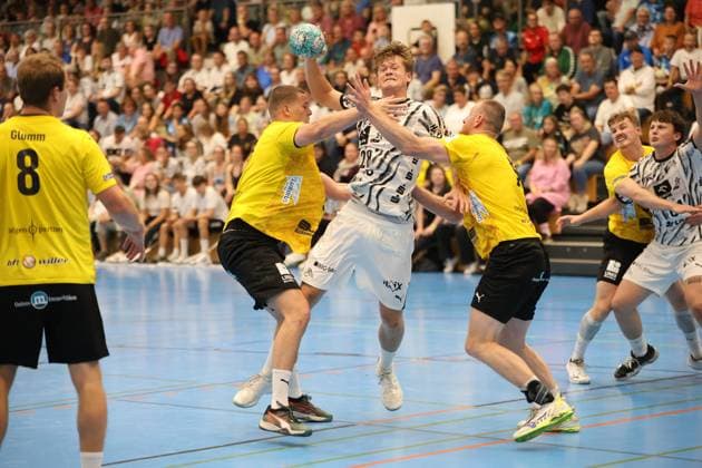 Julius Eisend vom THW Kiel springt mit dem Ball hoch und versucht, sich durch einen Doppelblock zweier Altenholz-Verteidiger in Gelb-Schwarz durchzusetzen. Die Szene zeigt intensiven Körperkontakt vor vollbesetzten Zuschauerrängen in der Edgar Meschkat Halle. Julius Eisend ( 28) im Sprungwurf gegen TSV Altenholz-Doppelblock *** Julius Eisend of THW Kiel jumps high with the ball and tries to break through a double block by two Altenholz defenders in yellow and black. The scene shows intense physical contact in front of a packed crowd at the Edgar Meschkat Halle. Julius Eisend, No. 28, takes a jump shot against TSV Altenholz’s double block. Copyright: xspeedshotx