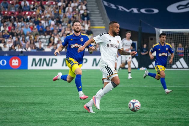 VANCOUVER, CANADA - AUGUST 19: Guilherme Augusto of Houston Dynamo FC controls the ball while Tristan Blackmon of Vancouver Whitecaps FC runs after him during the Major League Soccer match between Vancouver Whitecaps FC and Houston Dynamo FC at BC Place Stadium on August 19, 2026 in Vancouver, British Columbia, Canada.  Copyright: xAmyxElle SPPx Sportspressphoto_SPR211184