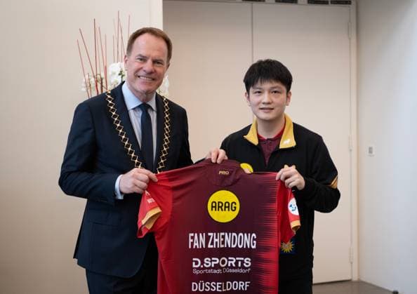 (260820) -- DUSSELDORF, Aug. 20, 2026 -- Fan Zhendong (R) gives his jersey to Stephan Keller, mayor of Dusseldorf, during the welcoming ceremony in Dusseldorf, Germany, Aug. 20, 2026. Chinese Table tennis, Tischtennis star Fan Zhendong was officially unveiled by his new club Borussia Dusseldorf at a press conference, PK, Pressekonferenz here on Thursday, as the Olympic champion prepares for his second season in the German Table Tennis Bundesliga and another campaign in European competition. ) (SP)GERMANY-DUSSELDORF-TABLE TENNIS-FAN ZHENDONG-CEREMONY ZhangxHaofu 