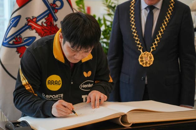 DUSSELDORF, GERMANY - AUGUST 20: Fan Zhendong (left) signs on the Golden Book during the welcoming ceremony held by his new club Borussia Dusseldorf on August 20, 2026 in Dusseldorf, Germany. Chinese Table tennis, Tischtennis star Fan Zhendong was officially unveiled by his new club Borussia Dusseldorf at a press conference, PK, Pressekonferenz on Thursday, as the Olympic champion prepares for his second season in the German Table Tennis Bundesliga and another campaign in European competition.  Copyright: xVCGx 111661096485