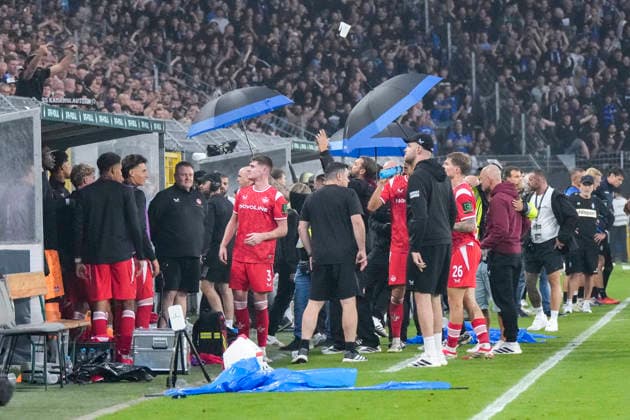 Spieler vom 1. FC Kaiserslautern müssen mit Regenschirmen vor geworfenen Gegenständen aus der Haupttribüne geschützt werden, Aktion, Action, Spielszene, 21.08.2026, Mannheim (Deutschland), Fussball, DFB-Pokal, 1. Runde, SV Waldhof Mannheim - 1. FC Kaiserslautern, DFB DFL REGULATIONS PROHIBIT ANY USE OF PHOTOGRAPHS AS IMAGE SEQUENCES AND OR QUASI-VIDEO. *** Players from 1 FC Kaiserslautern must be protected with umbrellas from objects thrown from the main stands; action, game scene, August 21, 2026, Mannheim, Germany, soccer, DFB Cup, 1st round, SV Waldhof Mannheim vs. 1 FC Kaiserslautern, DFB and DFL regulations prohibit any use of photographs as image sequences and or quasi-video xozx