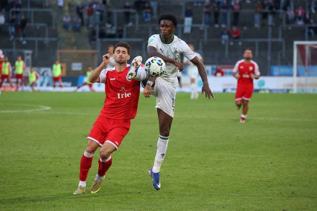 Elsamed Ramaj (SI) li. gegen Divine Dillon Berko (MG) re. Fussball Regionalliga West, 4. Spieltag, Sportfreunde Siegen - Borussia Moenchengladbach (Mönchengladbach) U23, am 21.08.2026 in Siegen Deutschland. *** Elsamed Ramaj (SI) vs. Divine Dillon Berko (MG) – Regional League West soccer, Matchday 4, Sportfreunde Siegen vs. Borussia Mönchengladbach U23, on August 21, 2026, in Siegen, Germany