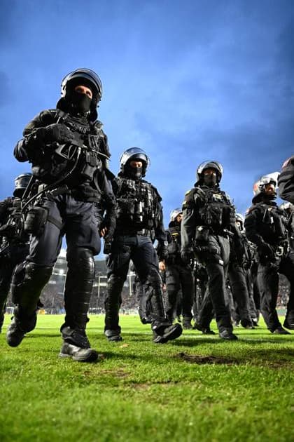 Mehrere Beamte der Bereitschaftspolizei in voller Schutzausrüstung mit Helmen und Körperpanzern marschieren über den Rasen des Carl-Benz-Stadions. Im Hintergrund sind die gefüllten Zuschauerränge zu erkennen. Polizeieinsatz auf dem Spielfeld im Carl-Benz-Stadion Mannheim *** Several riot police officers in full protective gear—including helmets and body armor—are marching across the lawn of the Carl Benz Stadium. In the background, the packed spectator stands can be seen. Police operation on the field at the Carl Benz Stadium in Mannheim Copyright: xMichaelxGelhardtx