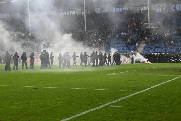 Eine große Gruppe Polizeibeamter in Schutzausrüstung steht auf dem Rasen des Carl-Benz-Stadions, während dichter Rauch von Pyrotechnik das Spielfeld einhüllt. Im Hintergrund sind Zuschauer auf den Tribünen zu sehen, vereinzelt brennt noch Pyrotechnik auf dem Platz. Polizeieinsatz auf dem Spielfeld im Carl-Benz-Stadion Mannheim *** A large group of police officers in protective gear stands on the lawn of the Carl Benz Stadium, while thick smoke from pyrotechnics engulfs the field. In the background, spectators can be seen in the stands, and a few pyrotechnics are still burning on the field. Police operation on the field at the Carl Benz Stadium in Mannheim Copyright: xMichaelxGelhardtx