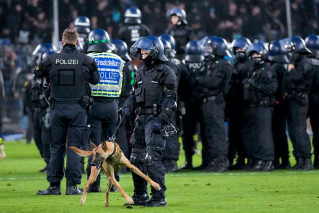 Polizisten sichern das Spielfeld nach Pyroattacken von den Rängen, Erhöhtes Polizeiaufkommen bei der Partie, Polizisten im Stadion, Polizeipräsenz, Polizeischutz, Polizei im Einsatz, Sicherheit, Stadionsicherheit, Symbolfoto, Symbolbild, Symbol, Risikospiel, Hochsicherheitsspiel, Fußballspiel mit einem erhöhten Sicherheitsrisiko, das Spiel wurde im Vorfeld als Hochrisikospiel eingestuft, Hundestaffel, Hundeführer, Polizei mit Hund, 21.08.2026, Mannheim (Deutschland), Fussball, DFB-Pokal, 1. Runde, SV Waldhof Mannheim - 1. FC Kaiserslautern, DFB DFL REGULATIONS PROHIBIT ANY USE OF PHOTOGRAPHS AS IMAGE SEQUENCES AND OR QUASI-VIDEO. *** Police officers secure the field following pyrotechnic attacks from the stands; increased police presence at the game; police officers in the stadium; police presence; police protection; police in action; security; stadium security, stock photo, stock image, symbol, high-risk match, high-security match, soccer match with an increased security risk, the match was classified as a high-risk match in advance, K-9 unit, K-9 handler, police with a dog, August 21, 2026, Mannheim, Germany, soccer, DFB Cup, 1st round, SV Waldhof Mannheim vs. 1. FC Kaiserslautern, DFB DFL REGULATIONS PROHIBIT ANY USE OF PHOTOGRAPHS AS IMAGE SEQUENCES AND OR QUASI-VIDEO xozx