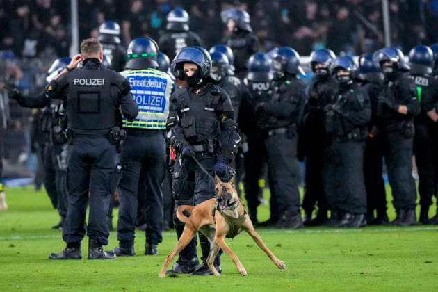Polizisten sichern das Spielfeld nach Pyroattacken von den Rängen, Erhöhtes Polizeiaufkommen bei der Partie, Polizisten im Stadion, Polizeipräsenz, Polizeischutz, Polizei im Einsatz, Sicherheit, Stadionsicherheit, Symbolfoto, Symbolbild, Symbol, Risikospiel, Hochsicherheitsspiel, Fußballspiel mit einem erhöhten Sicherheitsrisiko, das Spiel wurde im Vorfeld als Hochrisikospiel eingestuft, Hundestaffel, Hundeführer, Polizei mit Hund, 21.08.2026, Mannheim (Deutschland), Fussball, DFB-Pokal, 1. Runde, SV Waldhof Mannheim - 1. FC Kaiserslautern, DFB DFL REGULATIONS PROHIBIT ANY USE OF PHOTOGRAPHS AS IMAGE SEQUENCES AND OR QUASI-VIDEO. *** Police officers secure the field following pyrotechnic attacks from the stands; increased police presence at the game; police officers in the stadium; police presence; police protection; police in action; security; stadium security, stock photo, stock image, symbol, high-risk match, high-security match, soccer match with an increased security risk, the match was classified as a high-risk match in advance, K-9 unit, K-9 handler, police with a dog, August 21, 2026, Mannheim, Germany, soccer, DFB Cup, 1st round, SV Waldhof Mannheim vs. 1. FC Kaiserslautern, DFB DFL REGULATIONS PROHIBIT ANY USE OF PHOTOGRAPHS AS IMAGE SEQUENCES AND OR QUASI-VIDEO xozx