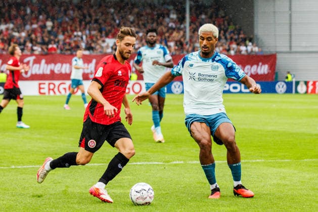 WIESBADEN, GERMANY - AUGUST 22: Lukas Schleimer (SV Wehen Wiesbaden, 7) and Loic Bade (Bayer 04 Leverkusen, 5) compete for the ball during the first-round match between SV Wehen Wiesbaden vs. Bayer 04 Leverkusen at Brita Arena of the German Cup on August 22, 2026 in Wiesbaden, Germany. DFL REGULATIONS PROHIBIT ANY USE OF PHOTOGRAPHS AS IMAGE SEQUENCES AND OR QUASI-VIDEO. Hessen Germany Copyright: xStephanxHahnex