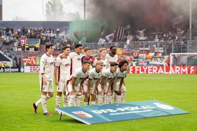 Fußball, Herren, Saison 2026 2027, DFB-Pokal (1. Runde), FC Energie Cottbus - FC Augsburg, Mannschaftsfoto Augsburg, Fans von Augsburg brennen Feuerwerk ab, 22.08.2026, *** Soccer, Men s, 2026–2027 Season, DFB Cup First Round, FC Energie Cottbus vs. FC Augsburg, Augsburg team photo, Augsburg fans setting off fireworks, August 22, 2026, Copyright: xMatthiasxKochx