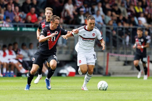 KOELN, GERMANY - AUGUST 22, 2026: Julian Justvan (1. FC Nuernberg, 10) tackled by Lucas Wolf (Viktoria Koeln, 21) during the DFB-Cup match between Viktoria Koeln vs. 1. FC Nuernberg at the Sportpark Hoehenberg on August 22, 2026 in Koeln, Germany. DFL REGULATIONS PROHIBIT ANY USE OF PHOTOGRAPHS AS IMAGE SEQUENCES AND OR QUASI-VIDEO. Nordrhein-Westfalen Germany Copyright: xAxelxKohringx
