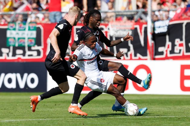 KOELN, GERMANY - AUGUST 22, 2026: Mohamed Alì Zoma (1. FC Nuernberg, 23) tackled by Meiko Sponsel (Viktoria Koeln, 19) and Yannick Tonye (Viktoria Koeln, 7) during the DFB-Cup match between Viktoria Koeln vs. 1. FC Nuernberg at the Sportpark Hoehenberg on August 22, 2026 in Koeln, Germany. DFL REGULATIONS PROHIBIT ANY USE OF PHOTOGRAPHS AS IMAGE SEQUENCES AND OR QUASI-VIDEO. Nordrhein-Westfalen Germany Copyright: xAxelxKohringx