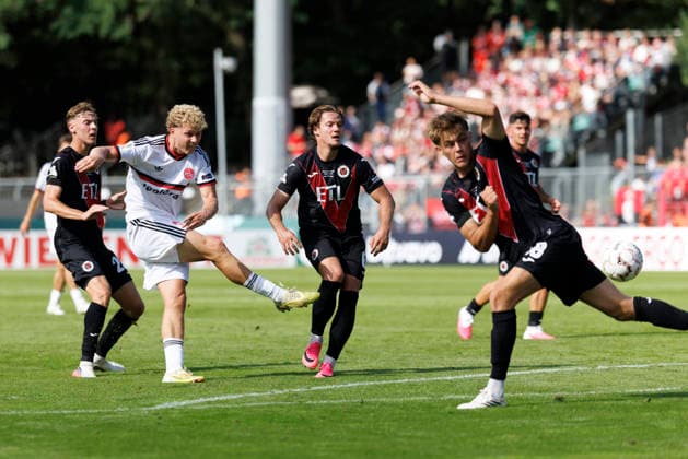 KOELN, GERMANY - AUGUST 22, 2026: Piet Scobel (1. FC Nuernberg, 19) with a shot, blocked by Tim Kloss (Viktoria Koeln, 18) during the DFB-Cup match between Viktoria Koeln vs. 1. FC Nuernberg at the Sportpark Hoehenberg on August 22, 2026 in Koeln, Germany. DFL REGULATIONS PROHIBIT ANY USE OF PHOTOGRAPHS AS IMAGE SEQUENCES AND OR QUASI-VIDEO. Nordrhein-Westfalen Germany Copyright: xAxelxKohringx