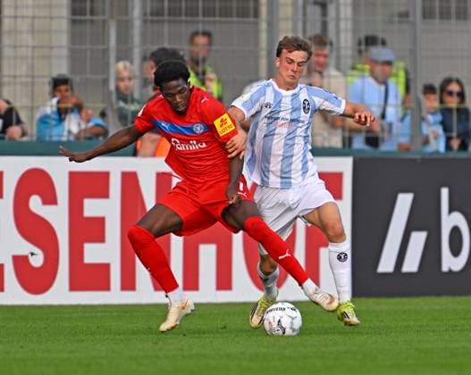 22.08.2026, Fussball DFB-Pokal 2026 27, 1.Runde, TSV 1860 München - Holstein Kiel, im Stadion an der Grünwalderstrasse in München, v.l. Faride Alidou (Holstein Kiel) gegen Julian Bell (TSV 1860 München) ***DFL and DFB regulations prohibit any use of photographs as image sequences and or quasi-video.*** *** August 22, 2026, 2026–27 DFB Cup, First Round, TSV 1860 Munich vs. Holstein Kiel, at the Stadion an der Grünwalderstrasse in Munich; from left: Faride Alidou (Holstein Kiel) vs. Julian Bell (TSV 1860 Munich) ***DFL and DFB regulations prohibit any use of photographs as image sequences and or quasi-video***