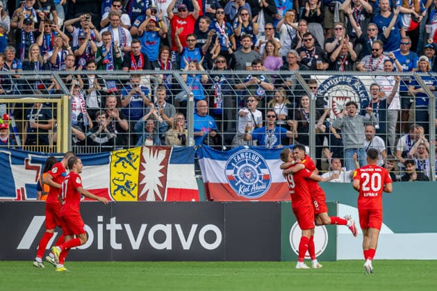 Die Kieler bejubeln vor der eigenen Fankurve mit Phil Harres (Holstein Kiel, 19) dessen Tor zum 0:1 GER, TSV 1860 Muenchen vs. Holstein Kiel, Fussball, DFB-Pokal, 1. Runde, Saison 2026 2027, 22.08.2026. (DFL DFB REGULATIONS PROHIBIT ANY USE OF PHOTOGRAPHS as IMAGE SEQUENCES and or QUASI-VIDEO). Foto: HMB Media Heike Feiner *** Kiel fans cheer in front of their own fan section as Phil Harre of Holstein Kiel, 19, scores the 0-1 goal (GER), TSV 1860 Munich vs. Holstein Kiel, Soccer, DFB Cup, 1st Round, 2026-2027 Season, August 22, 2026 DFL DFB regulations prohibit any use of photographs as image sequences and or quasi-video. Photo: HMB Media, Heike Feiner Copyright: HMBxMedia HeikexFeiner