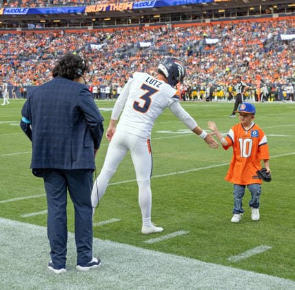 August 22, 2026, Denver, Colorado, USA: Broncos Kick-Off Kid gets a congrats from Broncos PK WIL LUTZ after bringing the tee back to the sidelines during the 1st. Half at Empower Field at Mile High Friday evening. Packers beat the Broncos in Pre-Season 33-13. Credit Image: ZUMA Press Wire) Denver USA - ZUMAav4_ 20260822_zaf_av4_042 Copyright: xHectorxAcevedox