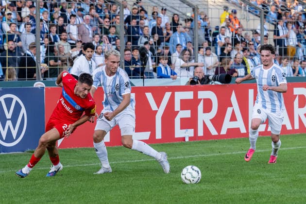 Kampf um den Ball Zweikampf zwischen Kampf um den Ball Zweikampf zwischen Lasse Fassmann (TSV 1860 Muenchen, 33) und Adrian Kapralik (Holstein Kiel, 20), dahinter Lance Fiedler (, TSV 1860 Muenchen, 47) GER, TSV 1860 Muenchen vs. Holstein Kiel, Fussball, DFB-Pokal, 1. Runde, Saison 2026 2027, 22.08.2026. (DFL DFB REGULATIONS PROHIBIT ANY USE OF PHOTOGRAPHS as IMAGE SEQUENCES and or QUASI-VIDEO). Foto: HMB Media Heike Feiner *** Battle for the ball: A tackle between Lasse Fassmann of TSV 1860 Munich, 33, and Adrian Kapralik of Holstein Kiel, 20; behind them is Lance Fiedler of TSV 1860 Munich, 47 GER, TSV 1860 Munich vs. Holstein Kiel, Soccer, DFB Cup, 1st Round, 2026–2027 Season, August 22, 2026 DFL DFB regulations prohibit any use of photographs as image sequences and or quasi-video. Photo: HMB Media, Heike Feiner Copyright: HMBxMedia HeikexFeiner