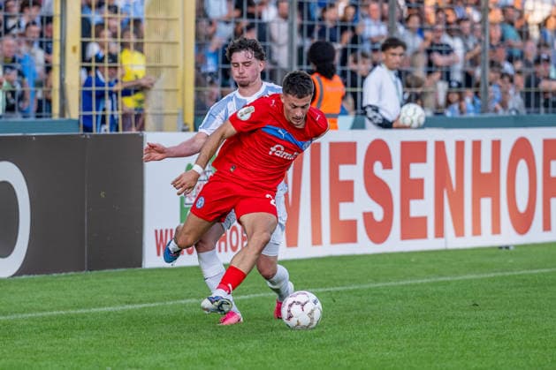 Kampf um den Ball Zweikampf zwischen Lance Fiedler (, TSV 1860 Muenchen, 47) und Adrian Kapralik (Holstein Kiel, 20) GER, TSV 1860 Muenchen vs. Holstein Kiel, Fussball, DFB-Pokal, 1. Runde, Saison 2026 2027, 22.08.2026. (DFL DFB REGULATIONS PROHIBIT ANY USE OF PHOTOGRAPHS as IMAGE SEQUENCES and or QUASI-VIDEO). Foto: HMB Media Heike Feiner *** Battle for the Ball: Tackle between Lance Fiedler (TSV 1860 Munich, 47) and Adrian Kapralik (Holstein Kiel, 20, GER), TSV 1860 Munich vs. Holstein Kiel, Soccer, DFB Cup, 1st Round, 2026–2027 Season, August 22, 2026. DFL and DFB regulations prohibit any use of photographs as image sequences and or quasi-video. Photo: HMB Media, Heike Feiner Copyright: HMBxMedia HeikexFeiner