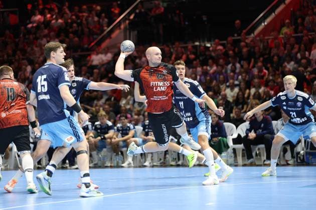 Melf Hagen ( 20; MTV Braunschweig) zieht in der Volkswagen Halle Braunschweig zum Sprungwurf hoch, umgeben von Dominik Axmann ( 15; HSV Hamburg), Nicolaj Jørgensen ( 11; HSV Hamburg) und Frederik Bo Andersen ( 21; HSV Hamburg). Die Abwehr der Hamburger versucht den Wurf zu blocken, während das Publikum die Szene hautnah verfolgt. Melf Hagen ( 20; MTV Braunschweig) im Sprungwurf gegen HSV Hamburg *** Melf Hagen 20 of MTV Braunschweig rises for a jump shot at the Volkswagen Halle in Braunschweig, surrounded by Dominik Axmann 15 of HSV Hamburg, Nicolaj Jørgensen 11 of HSV Hamburg, and Frederik Bo Andersen 21 of HSV Hamburg. The Hamburg defense tries to block the shot, while the crowd watches the action up close. Melf Hagen 20 of MTV Braunschweig attempts a jump shot against HSV Hamburg. Copyright: xspeedshotx