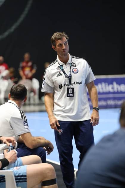 Torsten Jansen, Cheftrainer des HSV Hamburg, steht konzentriert an der Seitenlinie in der Volkswagen Halle in Braunschweig. Im Vordergrund sitzt ein Spieler des HSV Hamburg auf der Auswechselbank. Torsten Jansen (HSV Hamburg) beobachtet das Spielgeschehen von der Seitenlinie *** Torsten Jansen, head coach of HSV Hamburg, stands focused on the sidelines at the Volkswagen Halle in Braunschweig. In the foreground, an HSV Hamburg player sits on the bench. Torsten Jansen of HSV Hamburg watches the game from the sidelines. Copyright: xspeedshotx