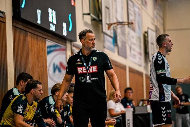 Ein Trainer der Rhein Neckar Löwen steht konzentriert an der Seitenlinie und beobachtet das Spielgeschehen, im Hintergrund sitzen Spieler auf der Auswechselbank. Rechts im Bild ist ein Spieler von SV Salamander Kornwestheim zu sehen. Trainer an der Seitenlinie beim Spiel in der Sporthalle Ost Kornwestheim *** A coach for the Rhein Neckar Löwen stands focused on the sideline, watching the game unfold; in the background, players are seated on the bench. On the right side of the picture is a player from SV Salamander Kornwestheim. Coach on the sideline during the game at the Sporthalle Ost in Kornwestheim Copyright: xspeedshotx xDorianfrickx