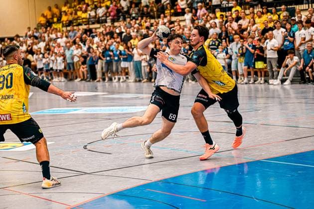 Finn Joneleit ( 69; SV Salamander Kornwestheim) zieht in der vollbesetzten Sporthalle Ost Kornwestheim zum Wurf hoch, während Robert Timmermeister ( 7; Rhein Neckar Löwen) von hinten Druck macht. Ein weiterer Löwen-Spieler ( 80) versucht von links zu stören. Finn Joneleit ( 69; SV Salamander Kornwestheim) im Wurf gegen Robert Timmermeister *** Finn Joneleit 69 of SV Salamander Kornwestheim lines up for a shot in the packed Sporthalle Ost Kornwestheim, while Robert Timmermeister (7) of the Rhein Neckar Löwen applies pressure from behind. Another Löwen player (80) tries to disrupt Finn Joneleit (69) of SV Salamander Kornwestheim as he takes his shot against Robert Timmermeister. Copyright: xspeedshotx xDorianfrickx