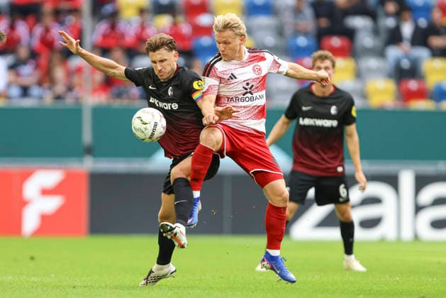 Lukas Kuebler (SC Freiburg) nd Andreas Mueller (Fortuna Duesseldorf) im Zweikampf waehrend des Spiels der 1. Runde des DFB-Pokal zwischen Fortuna Duesseldorf und SC Freiburg, Merkur Spiel-Arena am 23. August 2026 in Duesseldorf, Deutschland. (Foto von Oliver Kaelke DeFodi Images) +++ Lukas Kuebler (SC Freiburg) nd Andreas Mueller (Fortuna Duesseldorf) battle for the ball during the 1st round match of the DFB-Pokal between Fortuna Duesseldorf and SC Freiburg at Merkur Spiel-Arena on August 23, 2026 in Dusseldorf, Germany. (Photo by Oliver Kaelke DeFodi Images) DFB DFL REGULATIONS PROHIBIT ANY USE OF PHOTOGRAPHS AS IMAGE SEQUENCES AND OR QUASI-VIDEO. (Photo by Oliver Kaelke DeFodi Images) - *** Lukas Kuebler of SC Freiburg and Andreas Mueller of Fortuna Düsseldorf battle for the ball during the first-round DFB Cup match between Fortuna Düsseldorf and SC Freiburg at the Merkur Spiel Arena on August 23, 2026, in Düsseldorf, Germany. Photo by Oliver Kaelke, DeFodi Images. Lukas Kuebler of SC Freiburg and Andreas Mueller of Fortuna Düsseldorf battle for the ball during the first-round match of the DFB Cup between Fortuna Düsseldorf and SC Freiburg at Merkur Spiel Arena on August 23, 2026 in Düsseldorf, Germany. Photo by Oliver Kaelke, DeFodi Images. DFB and DFL regulations prohibit any use of photographs as image sequences and or quasi-video. Photo by Oliver Kaelke, DeFodi Images.