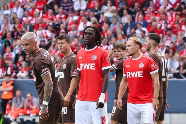 Franci Bouebari ( 19; Rot-Weiss Essen) und Tony Menzel ( 8; Rot-Weiss Essen) stehen vor dem Anpfiff auf dem Rasen des Stadions an der Hafenstraße, flankiert von Spielern des FC St. Pauli. Die Tribünen im Hintergrund sind mit rot-weißen RWE-Fans dicht besetzt. Franci Bouebari ( 19; Rot-Weiss Essen) und Tony Menzel ( 8; Rot-Weiss Essen) vor vollbesetzter Tribüne *** Franci Bouebari 19 Rot Weiss Essen and Tony Menzel 8 Rot Weiss Essen stand on the field at the stadium on Hafenstraße before kickoff, flanked by players from FC St. Pauli. The stands in the background are packed with red-and-white RWE fans. Franci Bouebari (No. 19, Rot-Weiss Essen) and Tony Menzel (No. 8, Rot-Weiss Essen) in front of a packed crowd. Copyright: xRuhr.Pottraitx